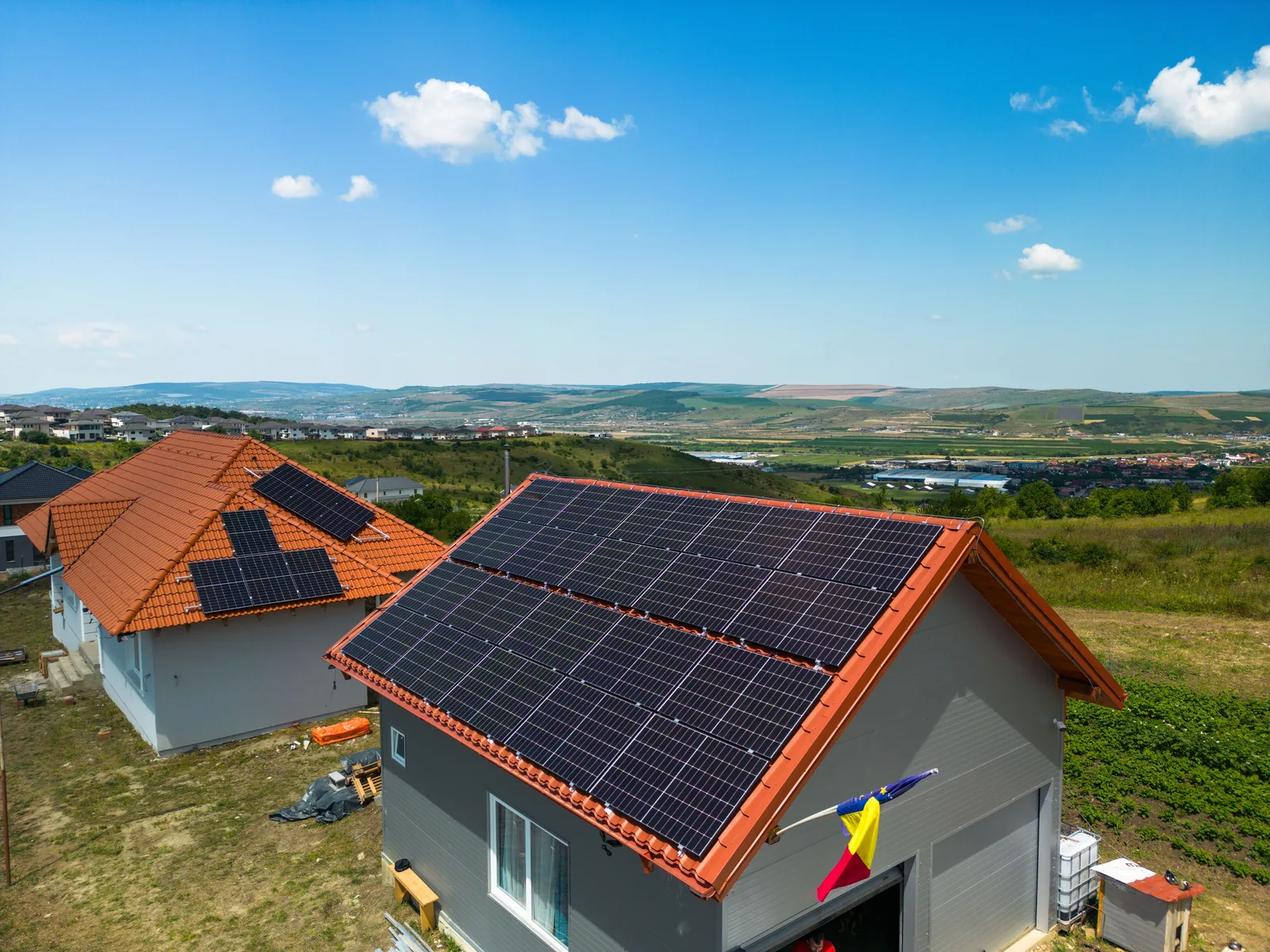 Sistem fotovoltaic montat pe acoperișul unei case din zona colinară a Clujului, cu panorama văii în fundal