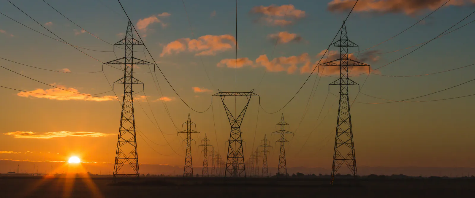 Stâlpi și linii electrice de înaltă tensiune la apus de soare